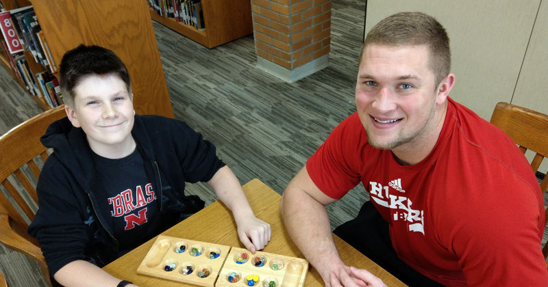A male mentor and mentee playing a game of mancala